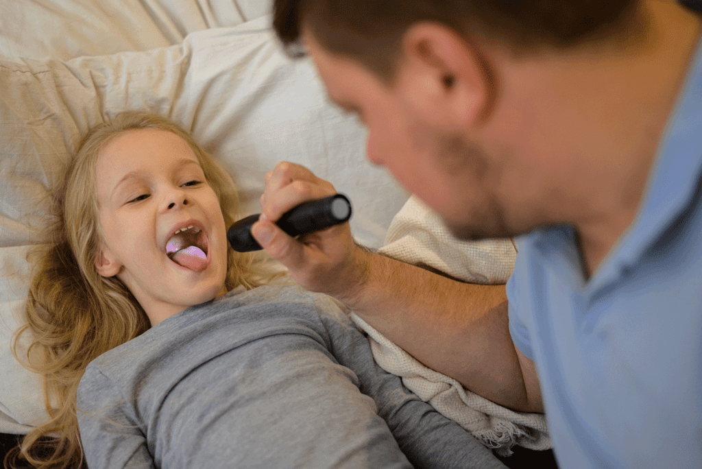 Dad Checks The Throat Of His Sick Child Shines A Flashlight So That It Is Better To See